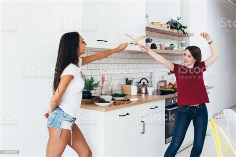 Two Woman Image That They Are Fighting On Swords By Wooden Spatulas In