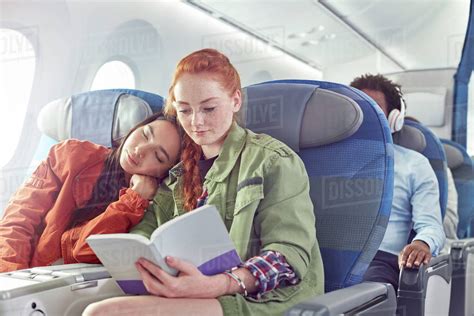 Affectionate Young Lesbian Couple Sleeping And Reading On Airplane
