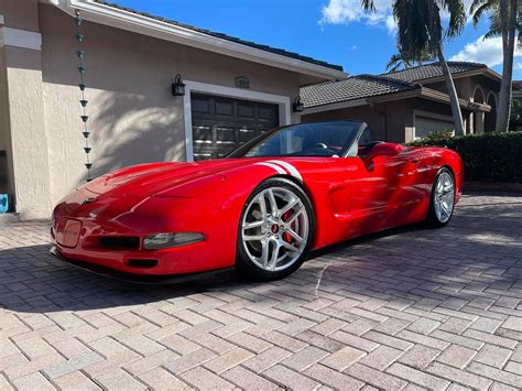 A Red Sports Car Is Parked In Front Of A House With Palm Trees On The