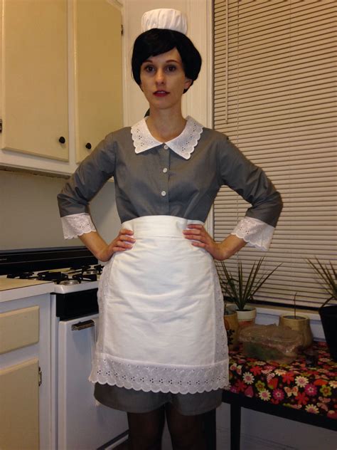 A Woman Standing In A Kitchen With Her Hands On Her Hips And Wearing An Apron