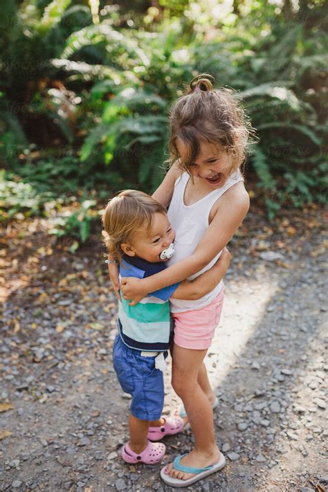 Cute Young Girl Hugging Toddler Brother Boy In Nature Outside In