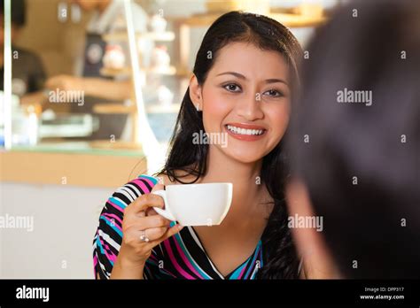 Asian Female Friends Enjoying Her Leisure Time In A Cafe Drinking Coffee Or Cappuccino And
