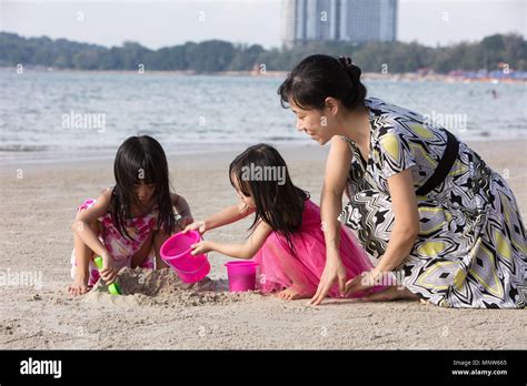 Asian Chinese Mum And Daughters Playing Sand Together At Beach Outdoor