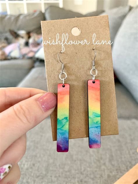 A Pair Of Colorful Earrings Sitting On Top Of A Piece Of Paper Next To