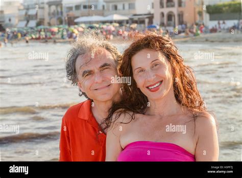 Tanned Mature Couple Smiling With Bathouse In The Background Stock