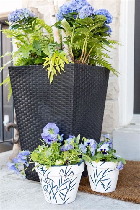 Two Planters With Blue Flowers Are Sitting On The Front Porch Next To