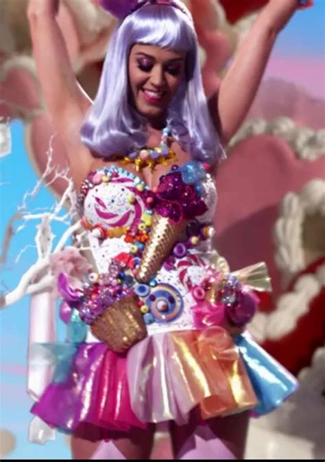 a woman dressed up as a candy land character with her arms in the air and holding two lollipops