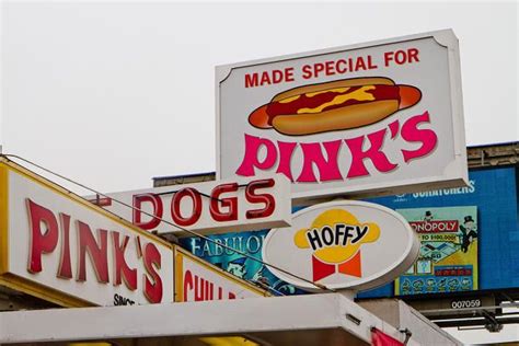 The Sign For Pinks Hot Dogs Is Shown Above Other Signs