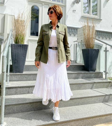 A Woman In A White Dress And Green Jacket Is Standing On Some Steps