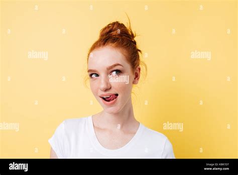 Tempting Ginger Woman In T Shirt Licking Her Lips And Looking Away Over Yellow Background Stock