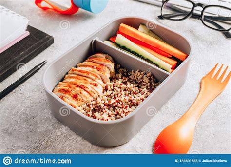 Healthy Meal Prep Containers With Quinoa Chicken And And Sticks Of Cucumber And Carrots On