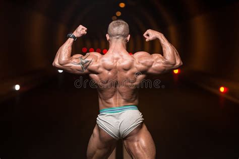 Bodybuilder Performing Rear Double Biceps Poses In Tunnel Stock Photo