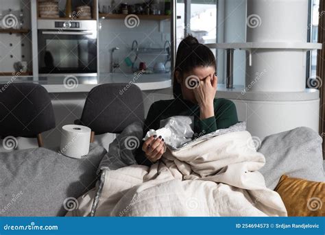 Young Sick Stressed Woman Lying At Home Covered With Blanket Blowing