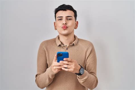 Non Binary Person Using Smartphone Typing Message Looking At The Camera