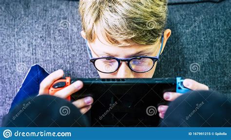 Young And Concentrated Caucasian Child Gamer With Portable Device