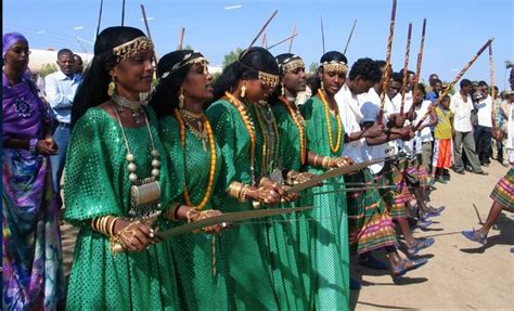 A Group Of Women Dressed In Green And Gold Holding Spears With Other