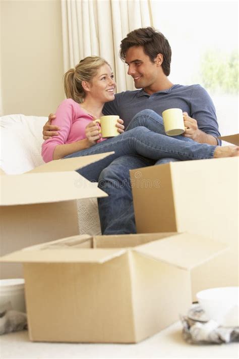 Young Couple Moving Into New Home Surrounded By Packing Boxes Stock