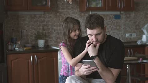 Happy Couple At Home In Kitchen At Breakfast Using Smartphone Together