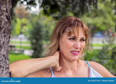Beautiful Mature Middle Aged Woman 50 Years Old Blonde Stands In The Park Against A Background