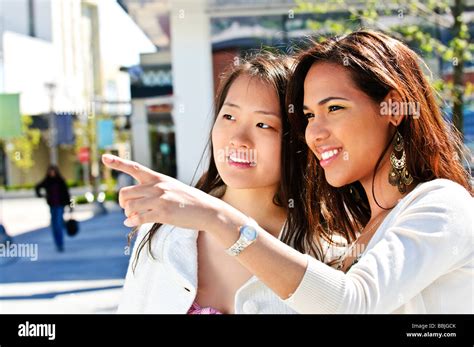 Two Young Girlfriends At Outdoor Mall Pointing Stock Photo Alamy