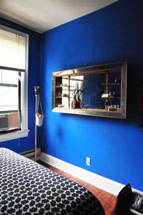 A Bedroom With Blue Walls And A Bed In Front Of A Large Mirror On The Wall