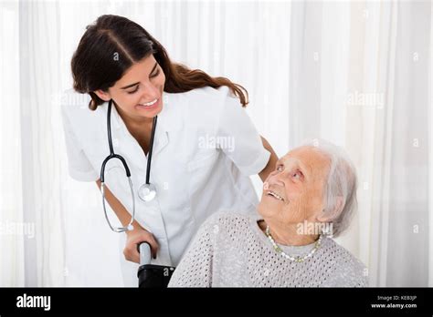Caring Female Doctor Helping Handicapped Senior Patient In Hospital