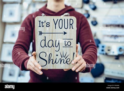 Man's hands holding motivational l's your day to shine message typing