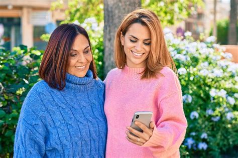 Hispanic Mother And Daughter Smiling Happy Using Smartphone At The Park