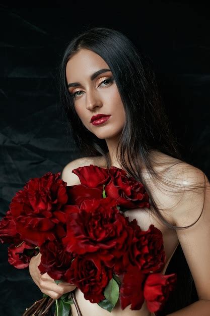 Sexy brünette mit einem strauß roter rosen auf dem boden lange haare