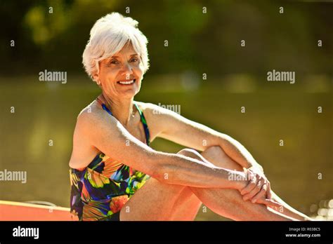 Porträt eines lächelnden älteren Frau sitzt neben einem See tragen