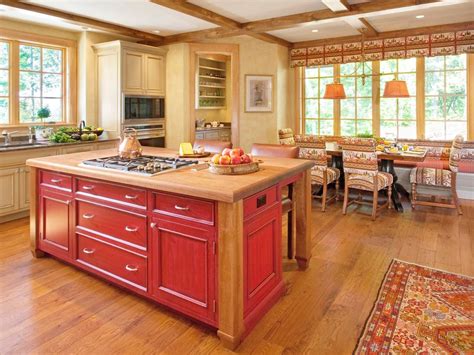 Contemporary large center island with gas range top, dark granite, wood baseboards. This eat-in kitchen features an oversized red island that ...