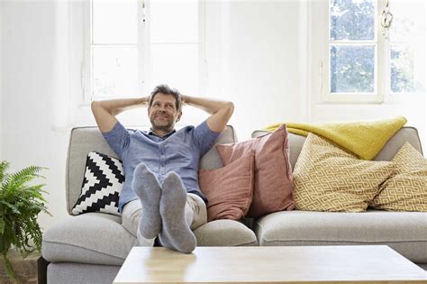 Man sitting on couch at home, relaxing - Stockphoto