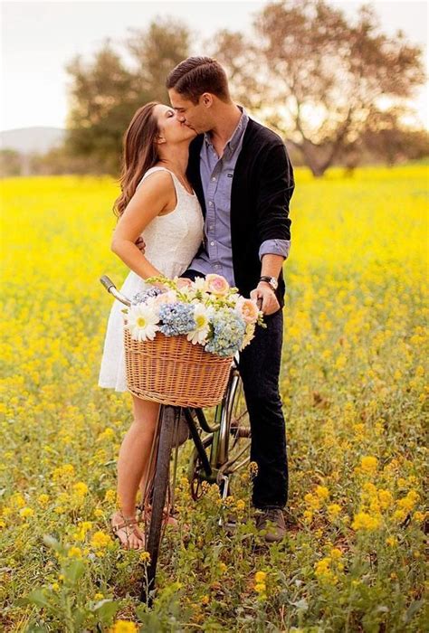 A Man And Woman Kissing On A Bike In A Field
