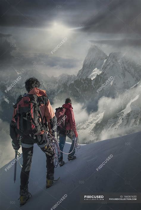 Two Climbers On A Snowy Slope Watching The Grand Jorasses In The Mont