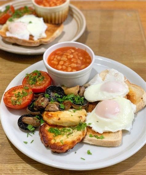 Two Plates With Eggs Toast Tomatoes And Beans On Them Sitting On A Table