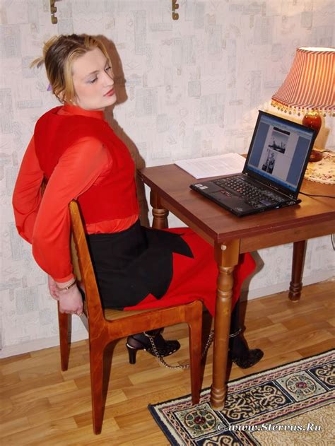 Woman On Chair Hands Cuffed Behind Back And Ankles Shackled Patiently Waits For Release