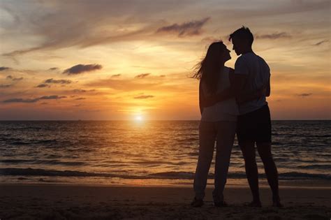 Premium Photo Silhouette Of Young Couple Standing On Beach Looks At