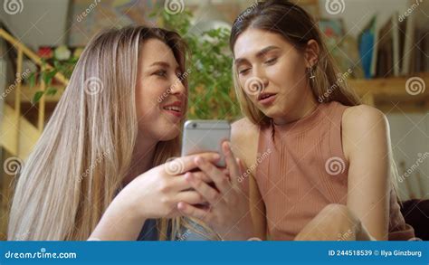 Two Pretty Lgbt Girls Are Sitting On The Sofa And Chatting With Their Friends On The Internet