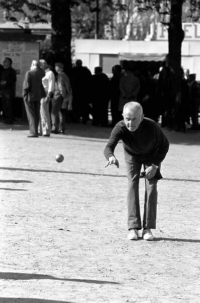 An Old Man Playing A Game Of Boules In A Street In Paris