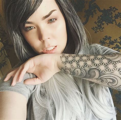 A Woman With Grey Hair And Tattoos On Her Arm