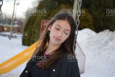 Photo Of A Teens Girl In A Swings Holding The Chain In A Public Park During A Period Of