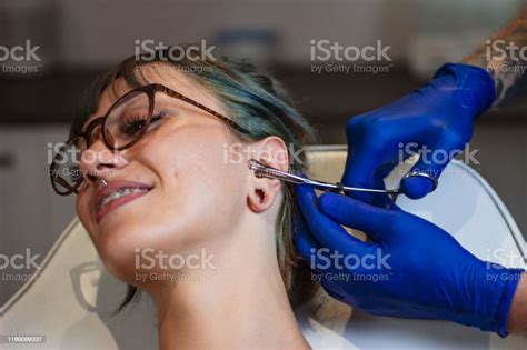 Portrait Of A Woman Getting Her Ear Pierced Man Showing A Process Of Piercing Ear Cleaning The