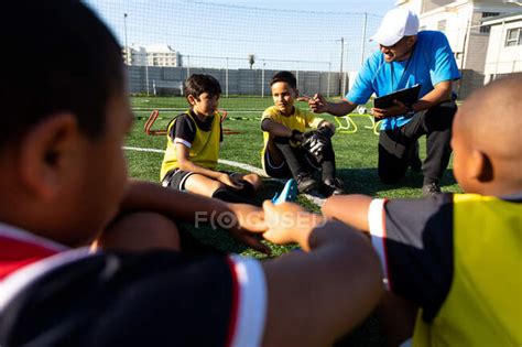Front View Of A Mixed Race Male Soccer Coach Kneeling And Instructing A