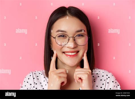 Beauty Concept Headshot Of Adorable Asian Girl In Trendy Glasses Smiling Poking Cheeks And