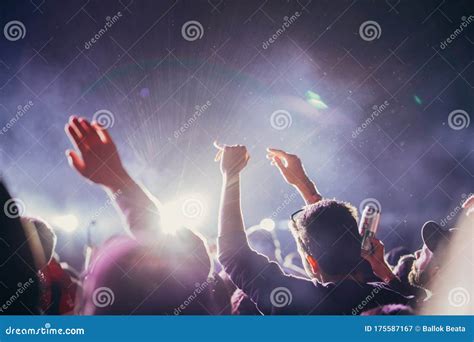 Stage Lights And Crowd Of Audience With Hands Raised At A Music