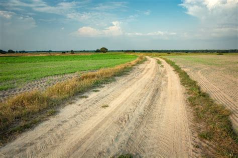 A Sandy Dirt Road Through Fields And Meadows The Horizon And Clouds On