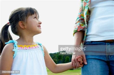 Woman Holding Daughters Hand In Park Girl Smiling Up At Mother High Res