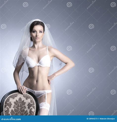 A Sexy Bride Posing In White Erotic Lingerie On A Chair Stock Photos