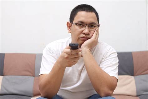 Unhappy Asian Man Sitting And Thinking On His Sofa At Home In The