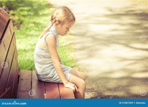 Trauriges Kleines Mädchen Das Auf Bank Im Park Sitzt Stockfoto Bild